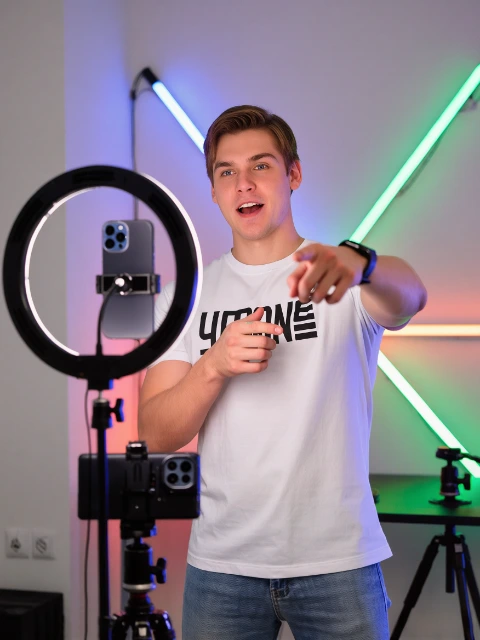 Illustrative photograph of a creator filming with a phone and ring light